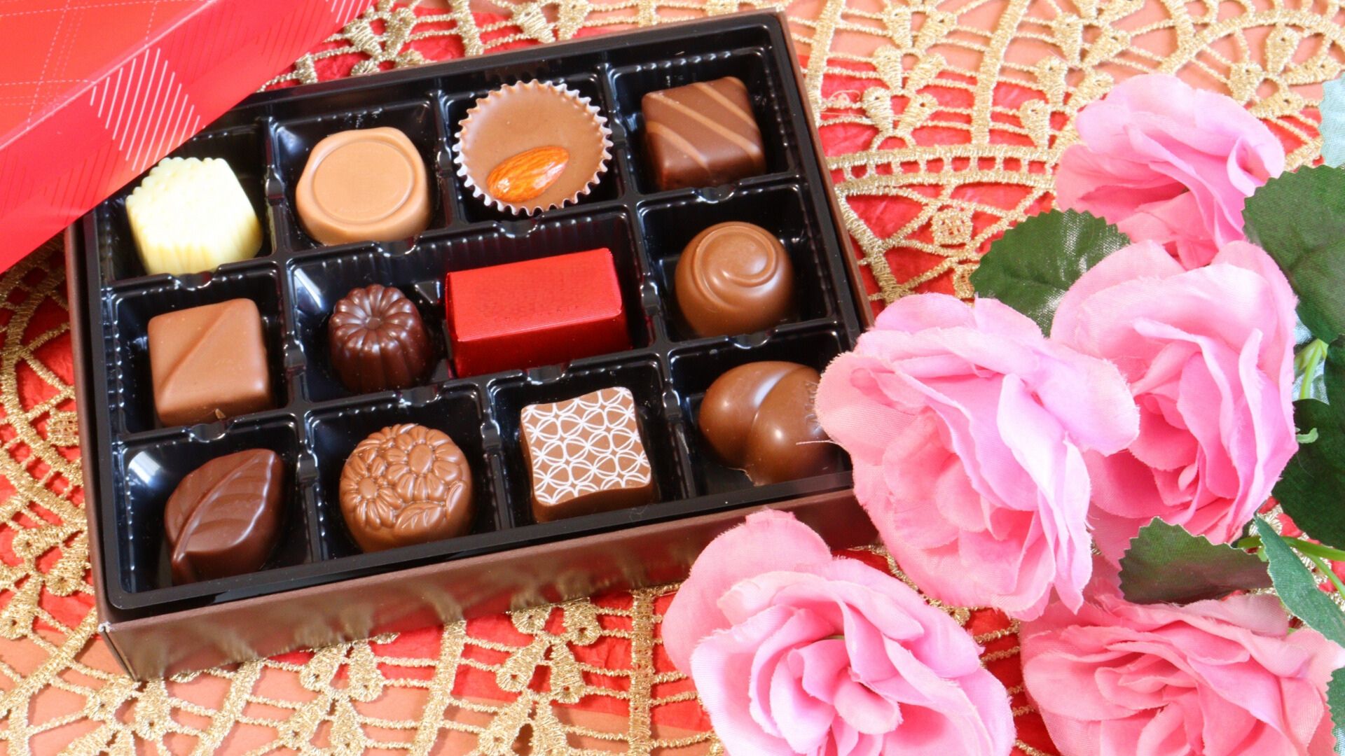 ギフトボックス入りのチョコレートとピンクの花が並ぶ、アムール・デュ・ショコラを想わせる華やかなイメージ写真