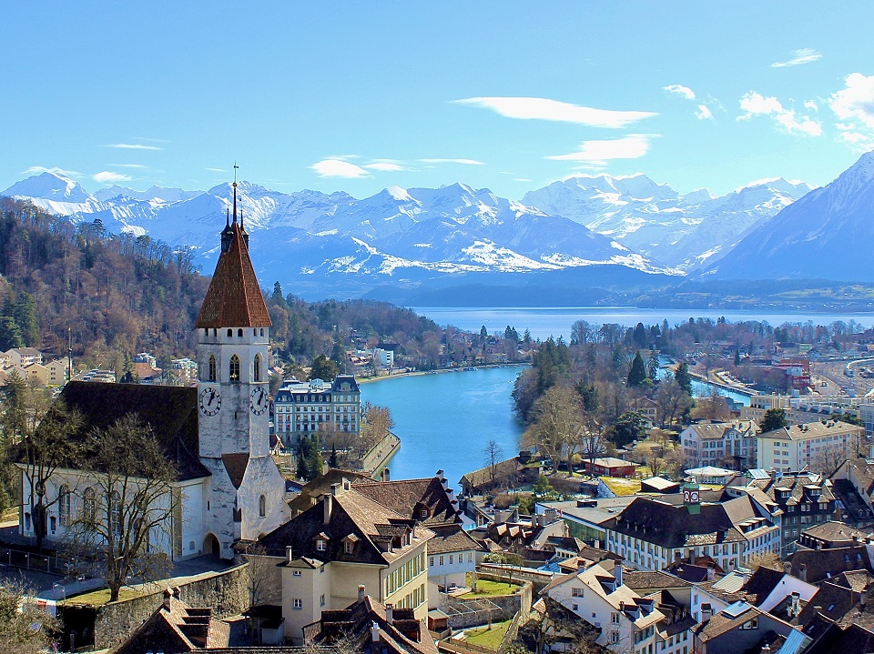 スイスの教会と遠くに広がるアルプス山脈の風景
