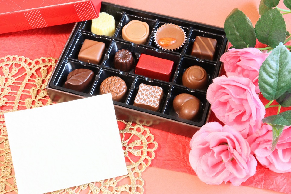 チョコレートの箱とピンクの花、メッセージカードが並ぶギフト写真。サロン・デュ・ショコラ2026のイメージ