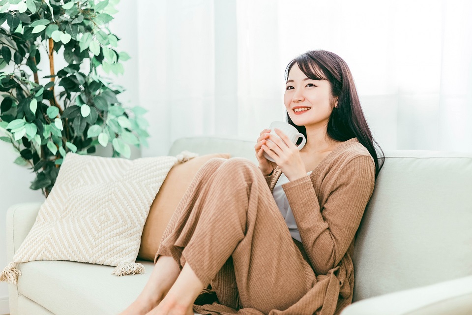 ソファでコーヒーを飲みながらくつろぐ女性の日常の暮らし