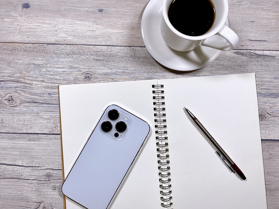 ノートとスマートフォン、コーヒーを並べた静かなセルフケアの時間をイメージした写真