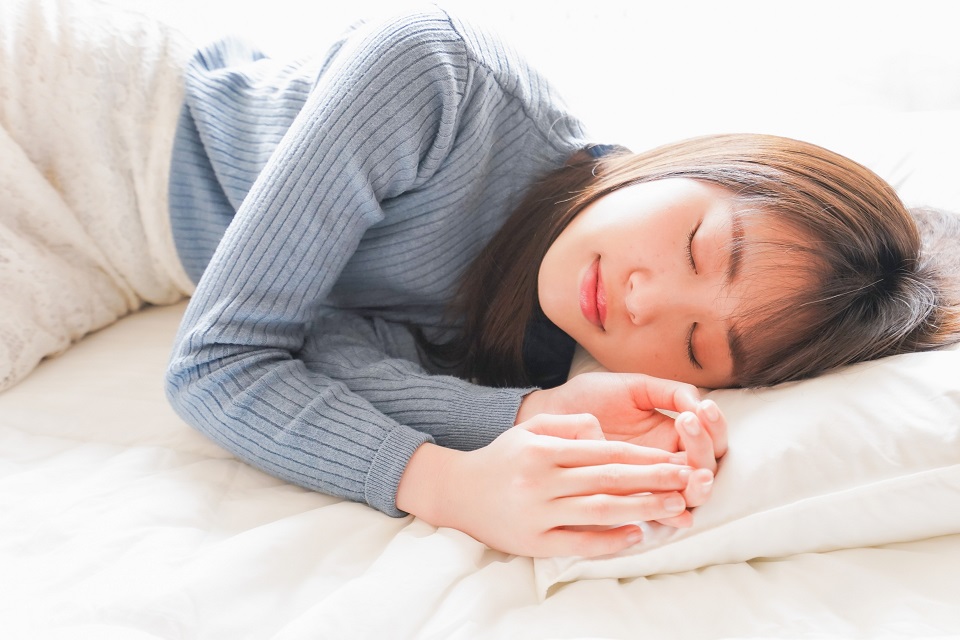ベッドで横向きに寝る女性