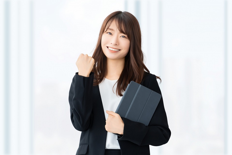 宅建試験の合格を目指してノートパソコンを持ちながらガッツポーズをする女性